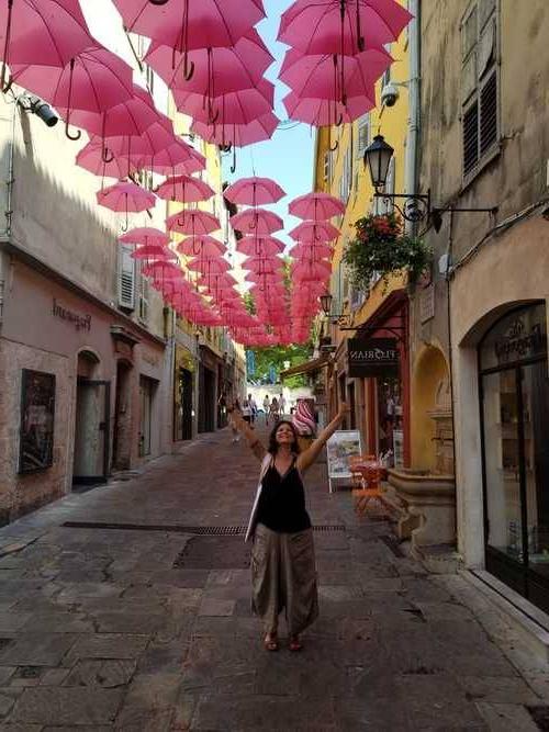 Melanie Benezet (French alumni) standing in a street under hundreds of open red umbrellas